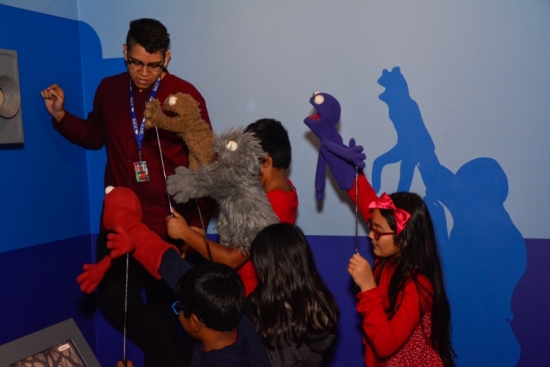 Museum educator shows young visitors how to perform with puppets