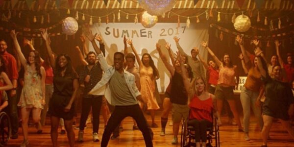 A school dance in front of a Summer 2017 banner, fronted by a boy standing on the left and a girl in a wheelchair on the right