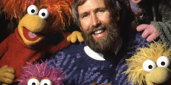 A smiling Jim Henson surrounded by Fraggles