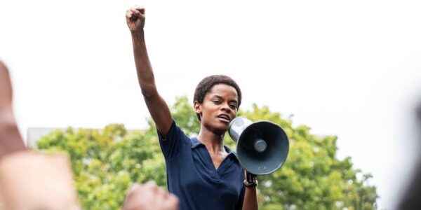A woman stands with her fist in the air, holding a megaphone
