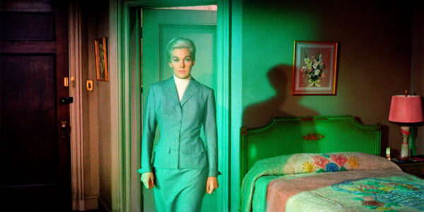Woman in a gray suit in a green room looking at camera
