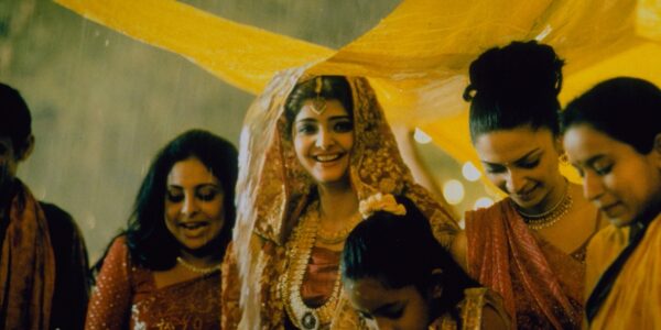 A woman smiles under a yellow canopy at a wedding
