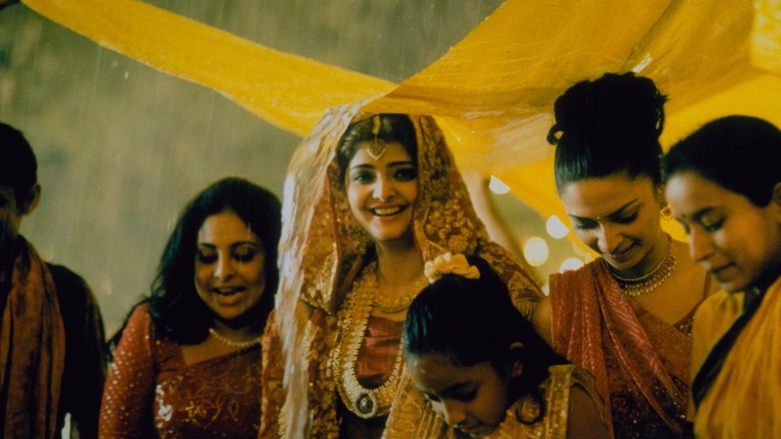 A woman smiles under a yellow canopy at a wedding