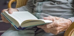 A close-up of elderly hands holding a book