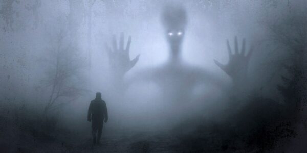 A ghost emerging in silhouette from the mist, with a small human figure in the foreground