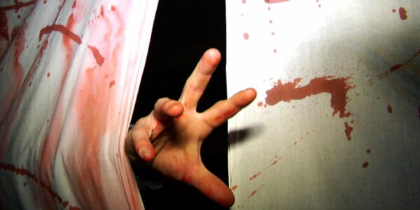 A hand reaching out from a bloody curtain in a haunted house
