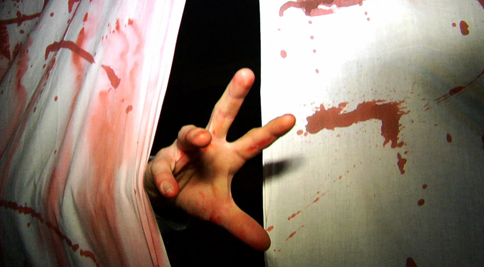 A hand reaching out from a bloody curtain in a haunted house