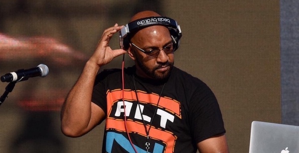 DJ Wiz wearing headphones and a T-shirt that says ALT