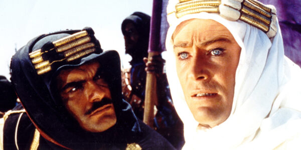 Two men in close-up: Peter O'Toole and Omar Sharif, the former wearing a white keffiyeh, the latter waring a black keffiyeh