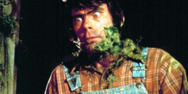 A man in overalls (Stephen King) looks off camera with a green beard made of moss