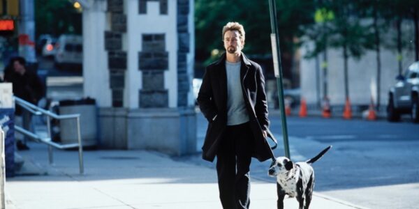 A jacketed man walking his dog down a New York city street