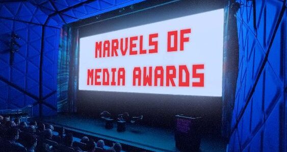 A theater showing a screen saying MARVELS OF MEDIA AWARDS in red font