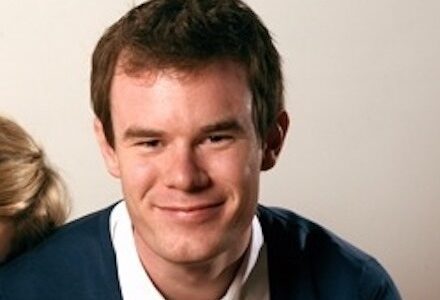 A young man, director Joe Swanberg, looks into the camera and smiles.