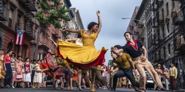 A woman in a yellow dress dancing in the New York streets, her arms raised as she spins.