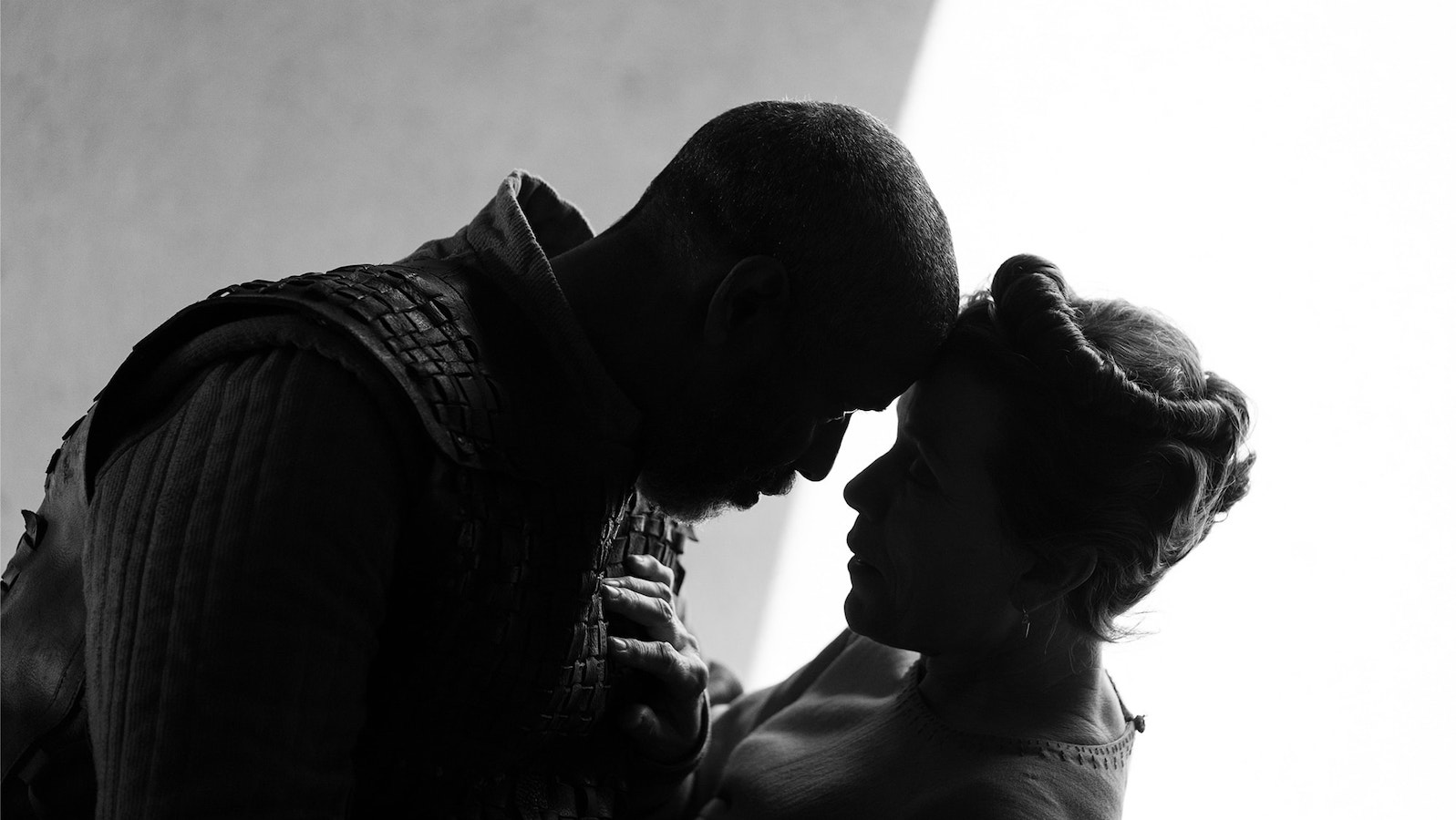 The silhouetted profiles of Macbeth and Lady Macbeth, their foreheads touching intimately.