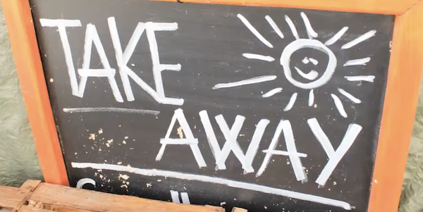 A restaurant chalkboard that says "Take Away" aside a drawing of a smiling sun.