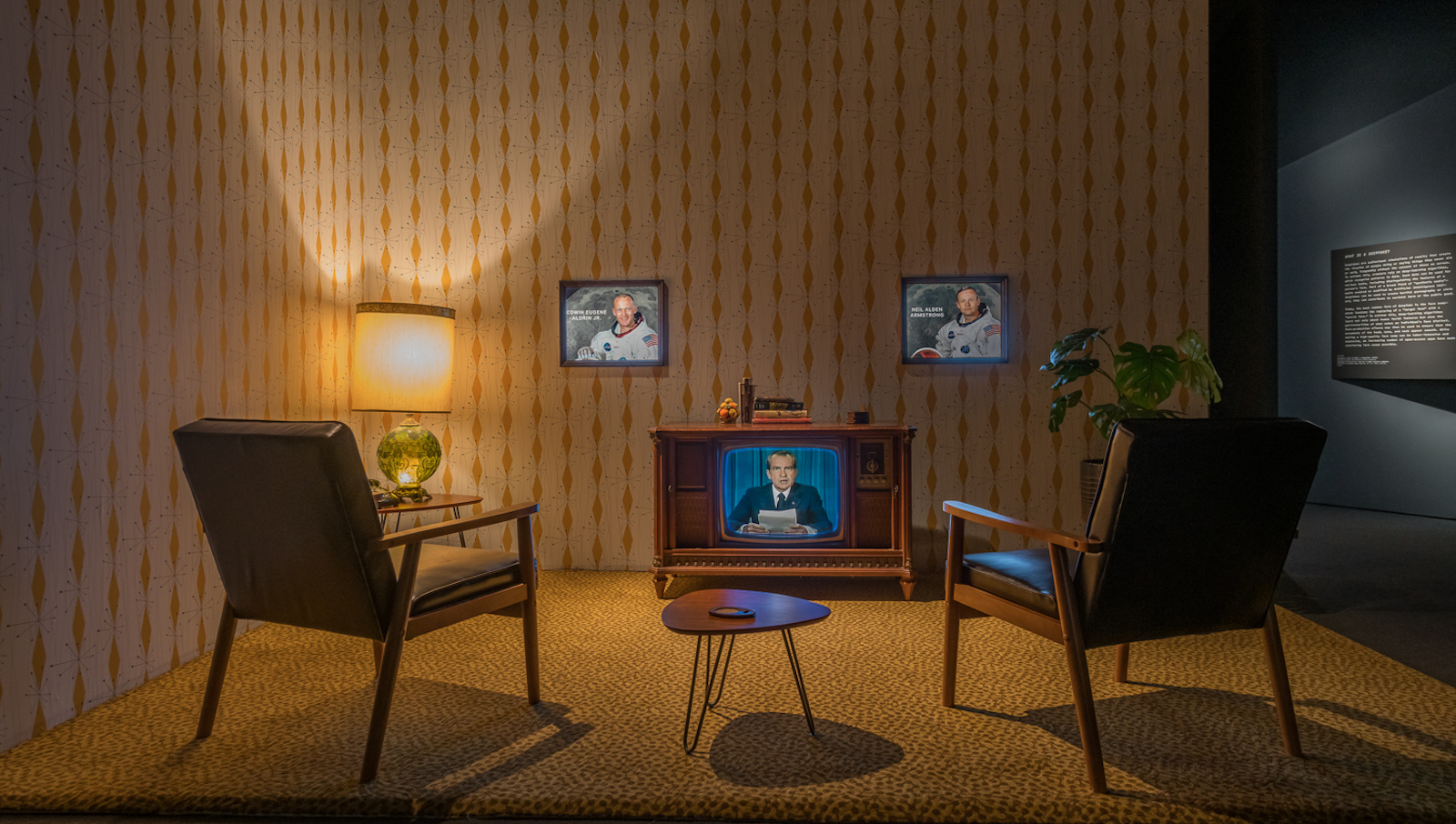 An exhibition mockup of a living room, with two chairs facing a television showing an image of President Nixon giving an address.