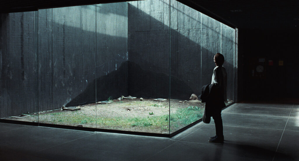 A woman looks at an installation work of glass and concrete.