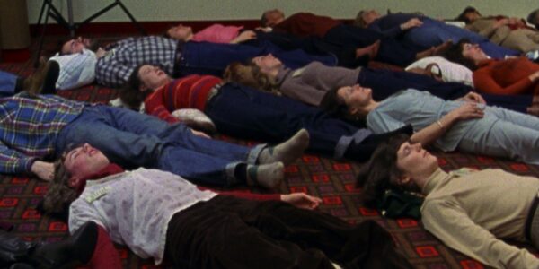A group of people lying on a floor, with their eyes closed