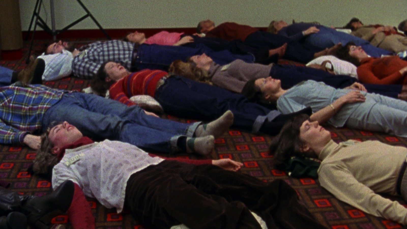 A group of people lying on a floor, with their eyes closed