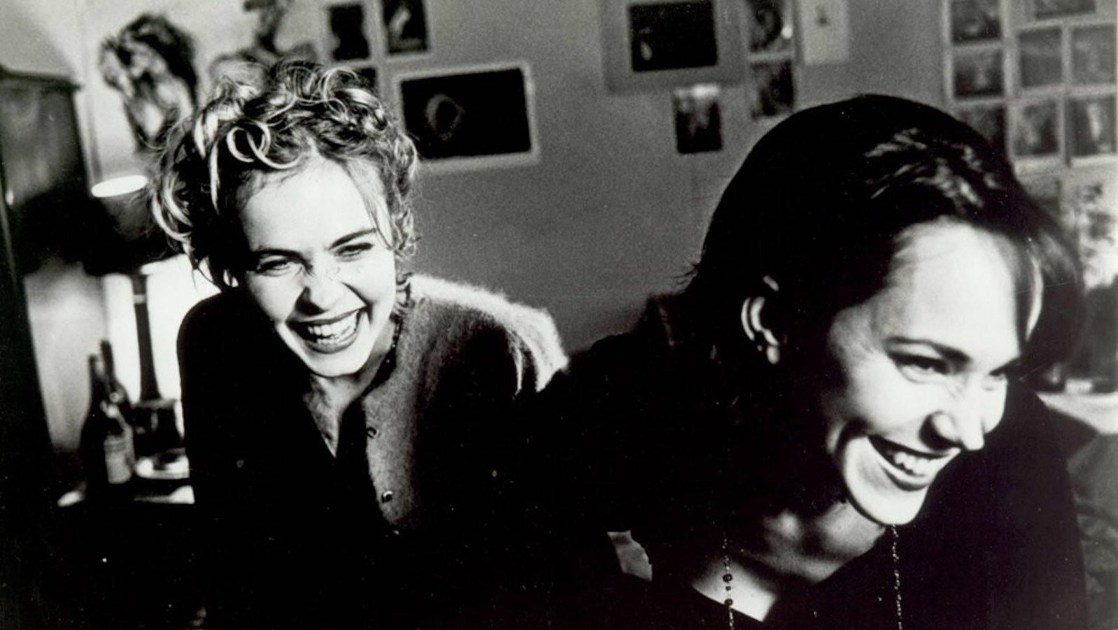A black and white image of two women laughing, both facing camera, one slightly in back of the other.