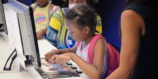 A young girl wearing a pink backpack makes an animation at a MoMI computer station