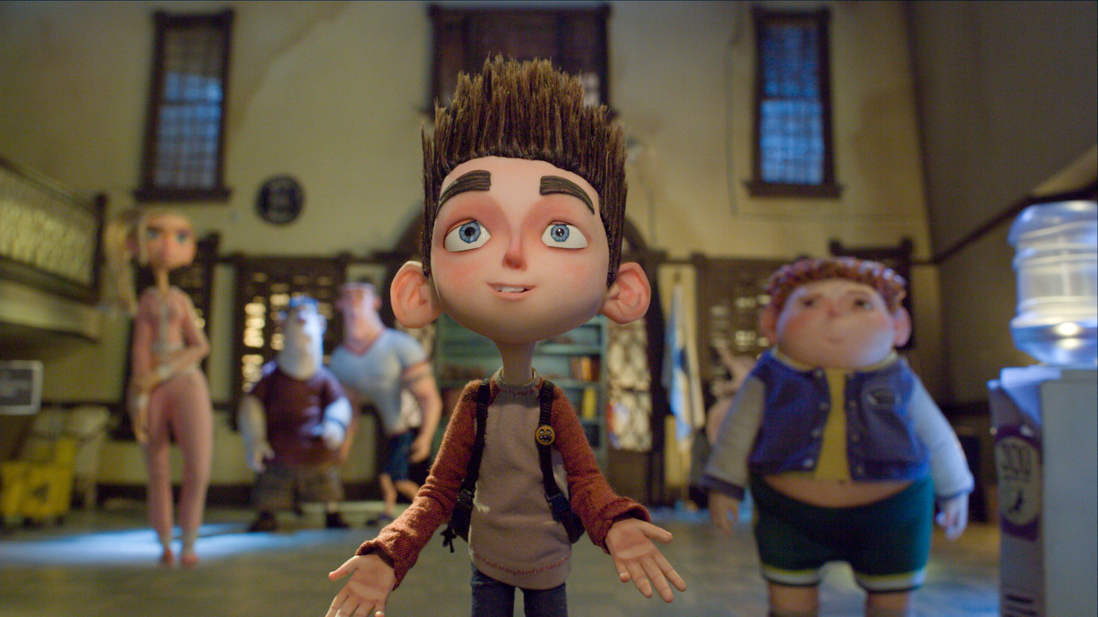 A stop-motion animated boy surrounded by his friends in the background, looking up towards the camera