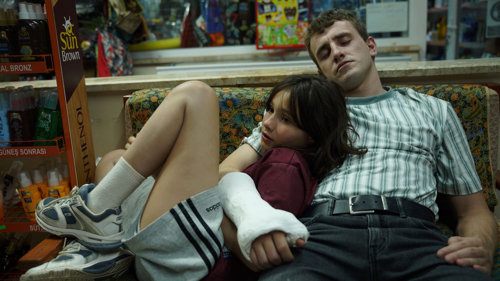 A man in an arm cast holding a young girl as they recline on a couch