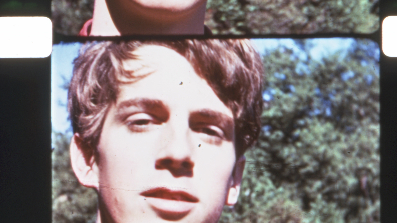 A close-up of a man on 16mm color film looking into camera.