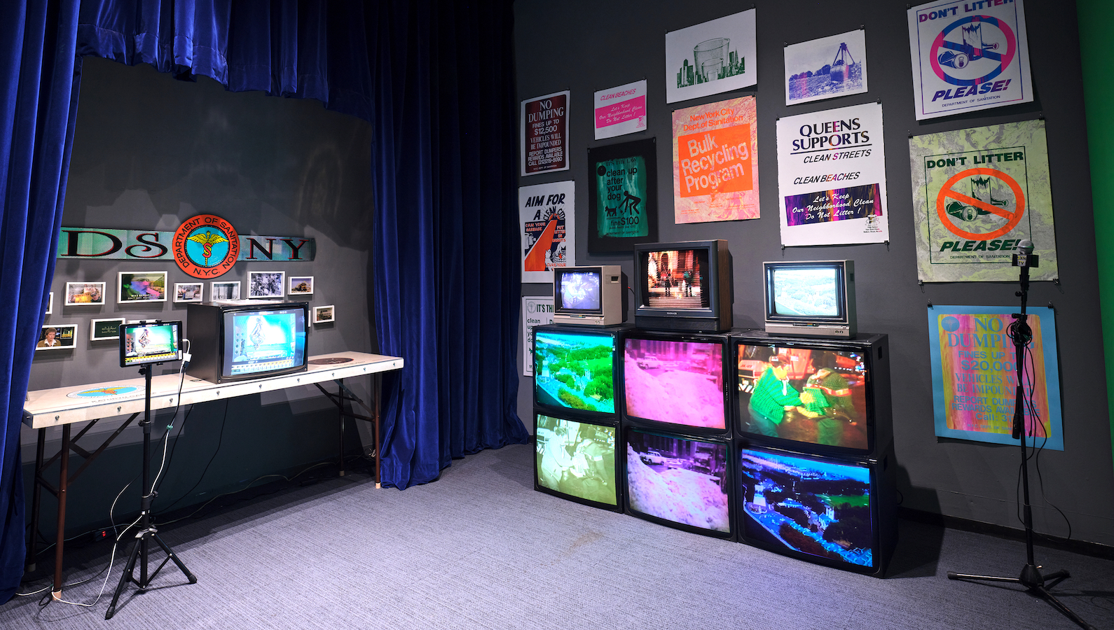 Six televisions broadcasting colorful images, stacked atop each other in two rows, with a computer screen on a desk to the left