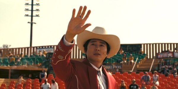 A man in a cowboy hat raises his hand at looks at the sky