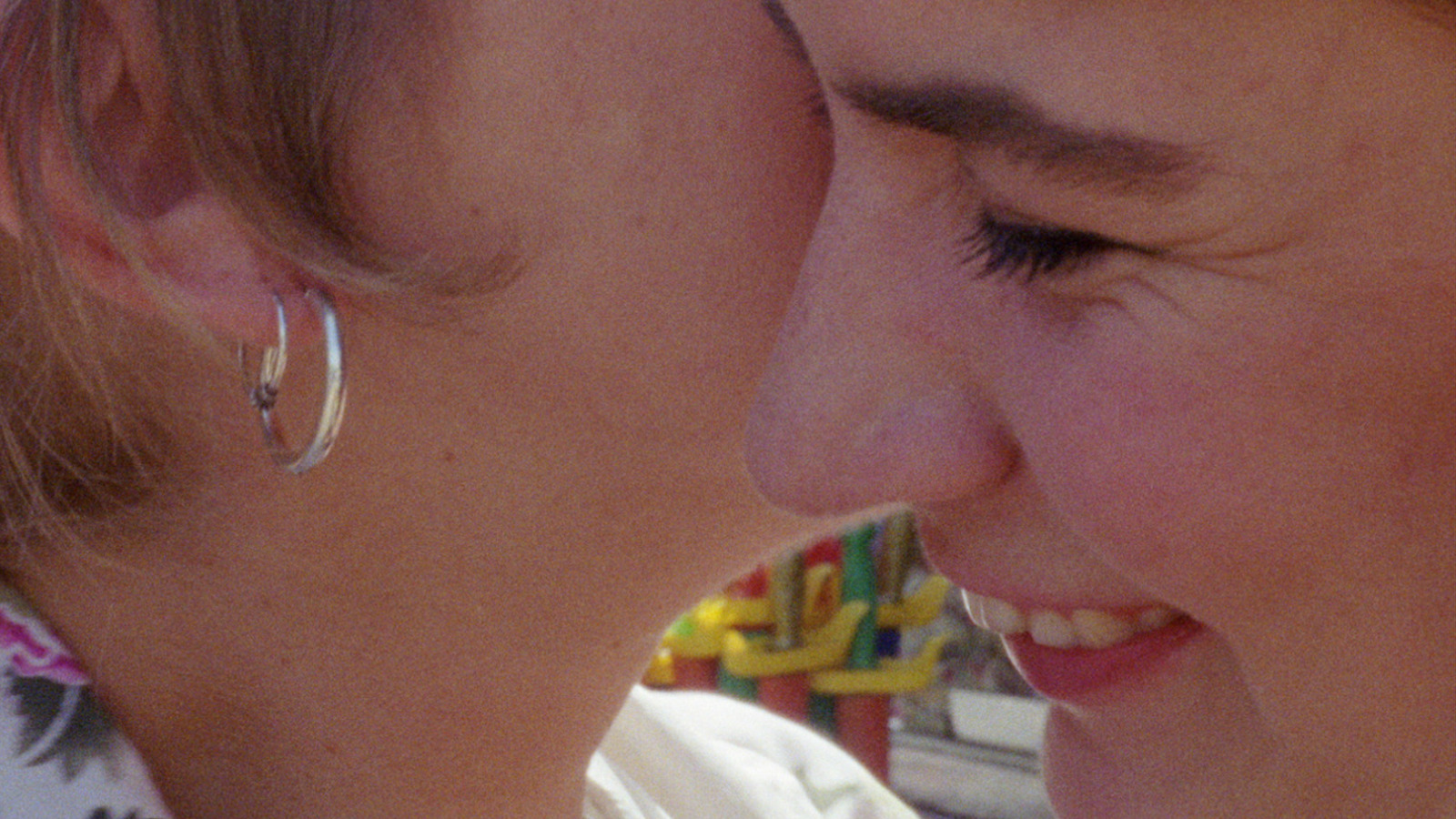 Extreme closeup of a woman whispering in another's ear in profile