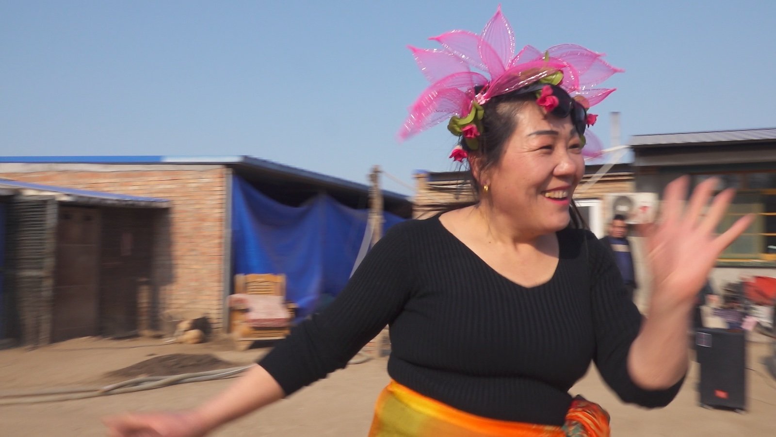 A woman with a flowery pink hat dances outside
