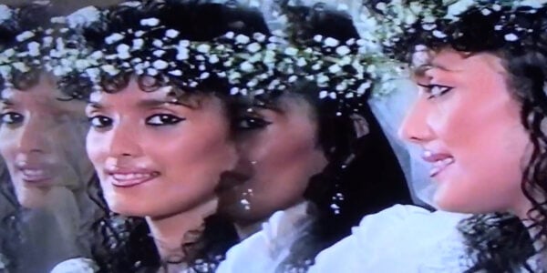 A low-grade video image of a woman in a wedding dress and flowers in her hair, her profile reflected prismatically across the screen
