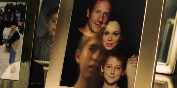 A child sees a reflection of himself in a framed photo of a family
