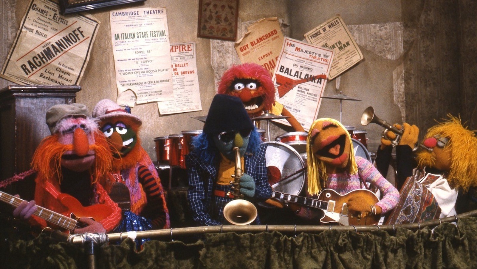 A muppet rock band play instruments—drums, guitars, horns.