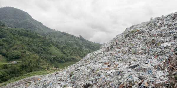 An image of a gigantic trash heap, as big as the green mountain next to it