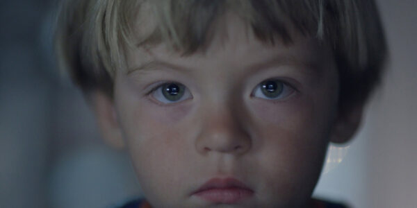 A young blond boy's face in closeup looking at camera
