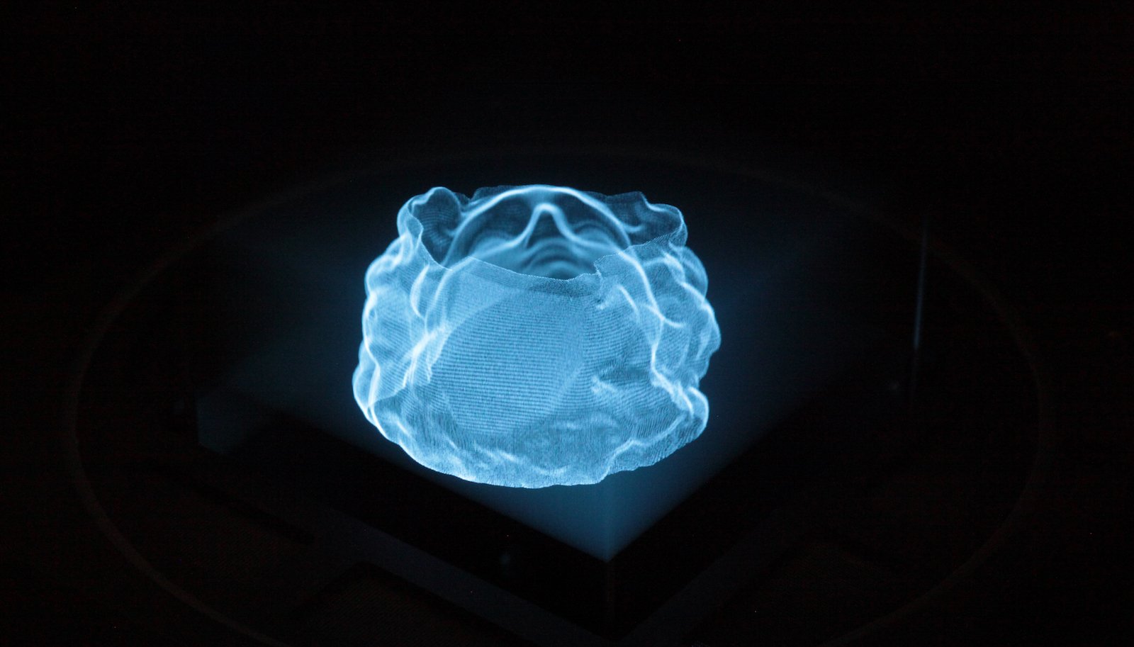 A holographic image of a head bust in blue against a black background