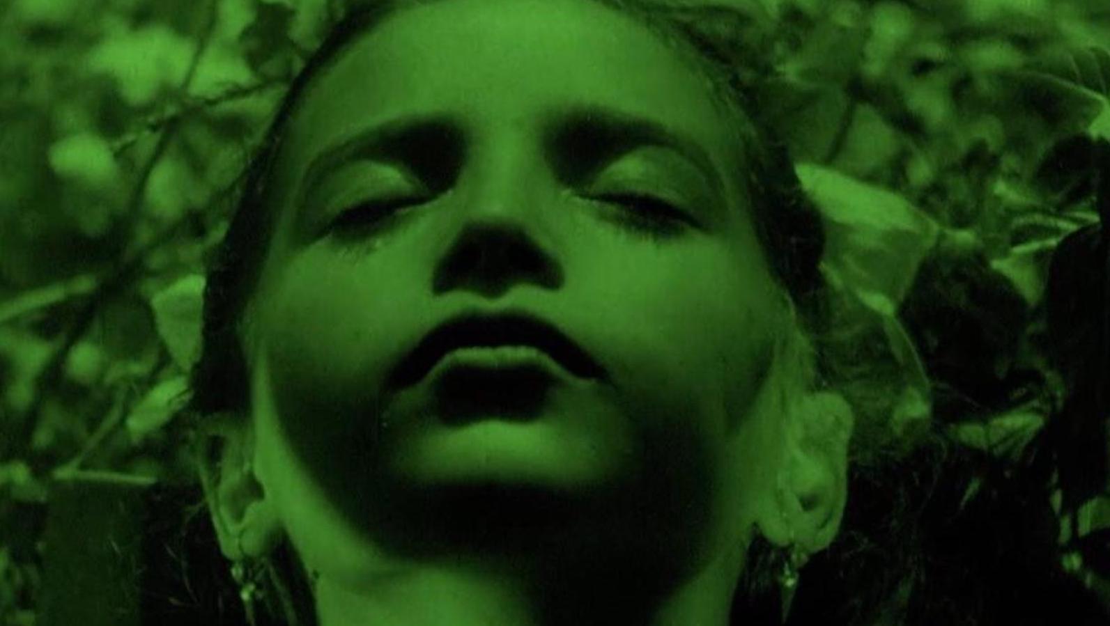 An image with a green filter of a young girl's face in extreme closeup, eyes closed,.