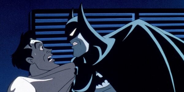 Batman grabs a frightened man by the shirt and scowls at him